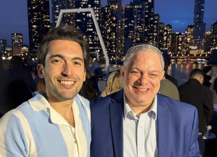 Two men are posing for a picture in front of a city skyline.