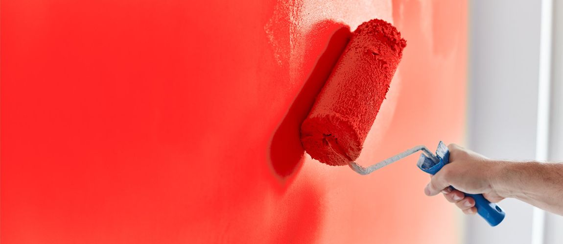 Professional Painter Painting a Wall With Red Paint