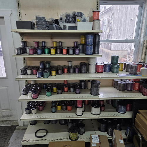 Shelves of colorful spools of thread in a workshop beside a window