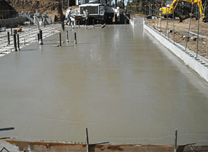 A concrete floor is being poured on a construction site.