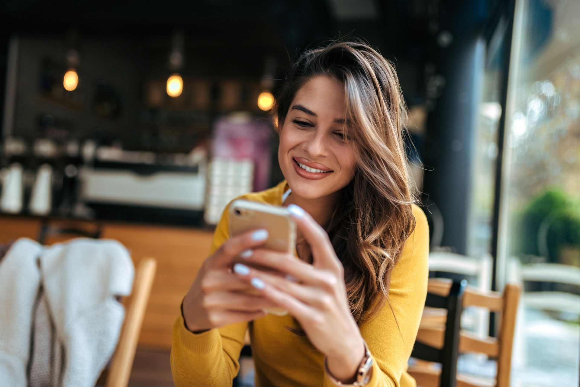 a woman is sitting at a table looking at her cell phone .