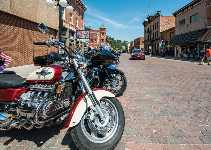 a row of motorcycles are parked on the side of a brick street .