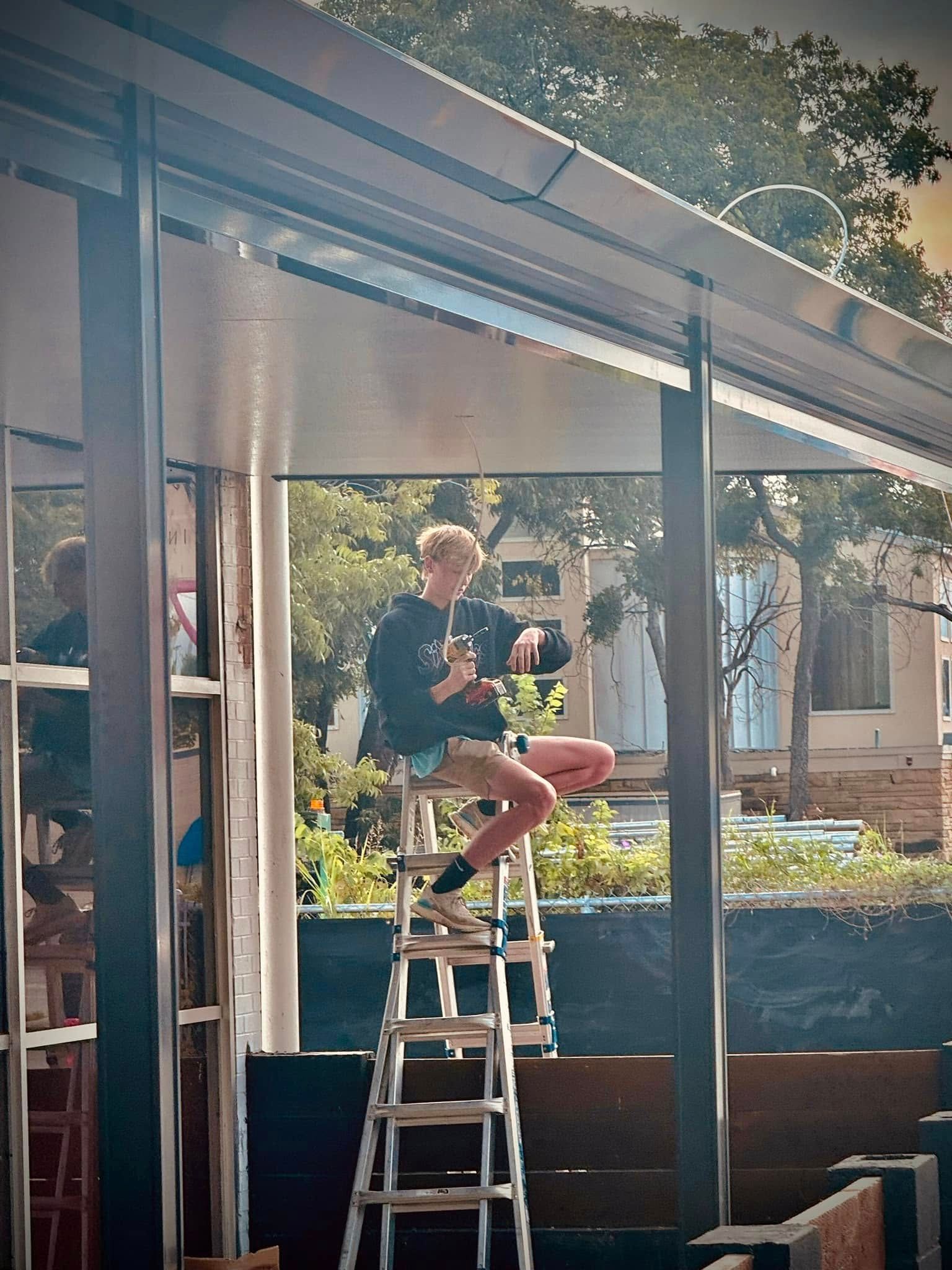 A man is sitting on a ladder in front of a building.