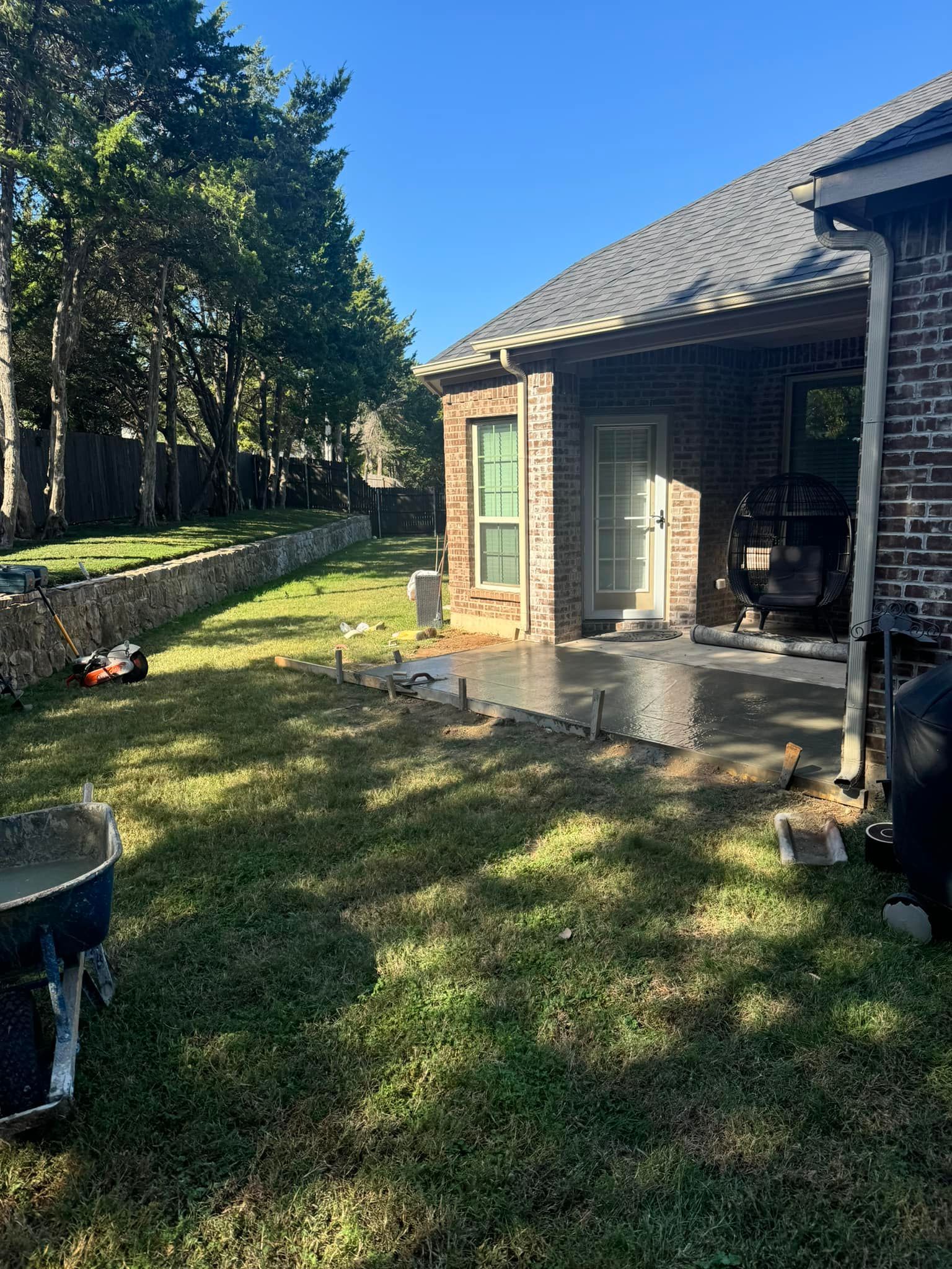 A brick house with a patio being built in the backyard.