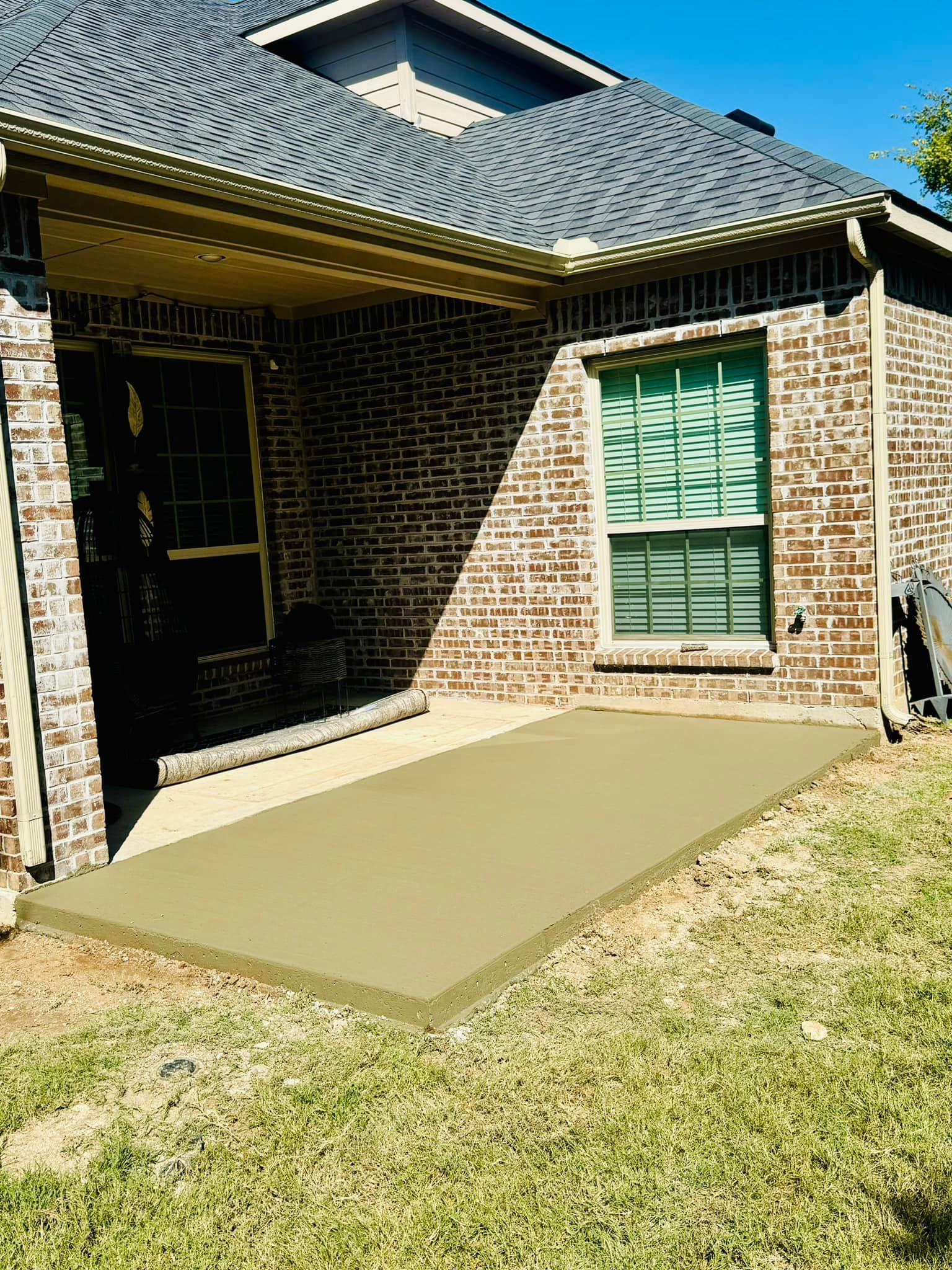 A brick house with a concrete patio in front of it.