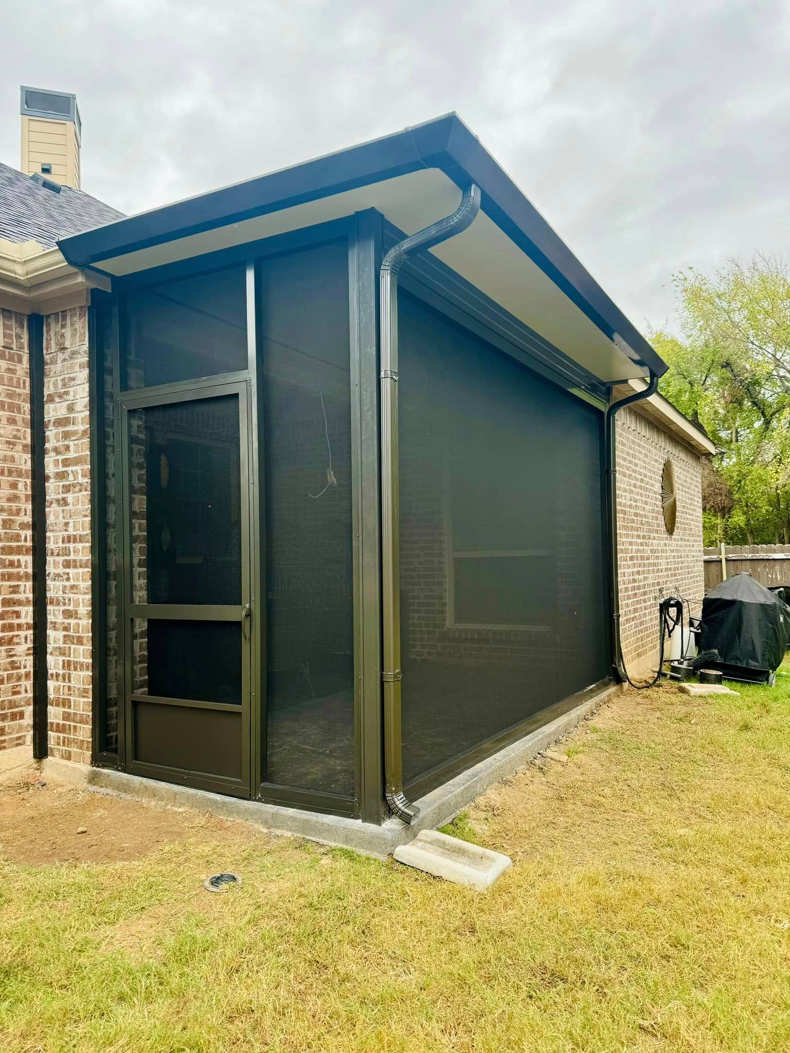 A screened in porch in the backyard of a house.