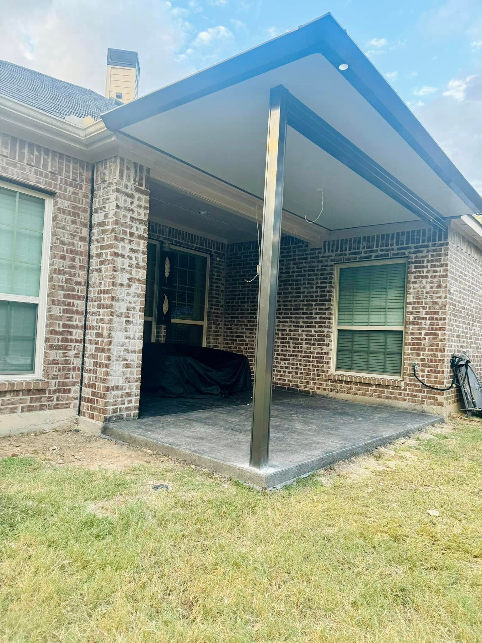 A brick house with a covered patio in front of it.