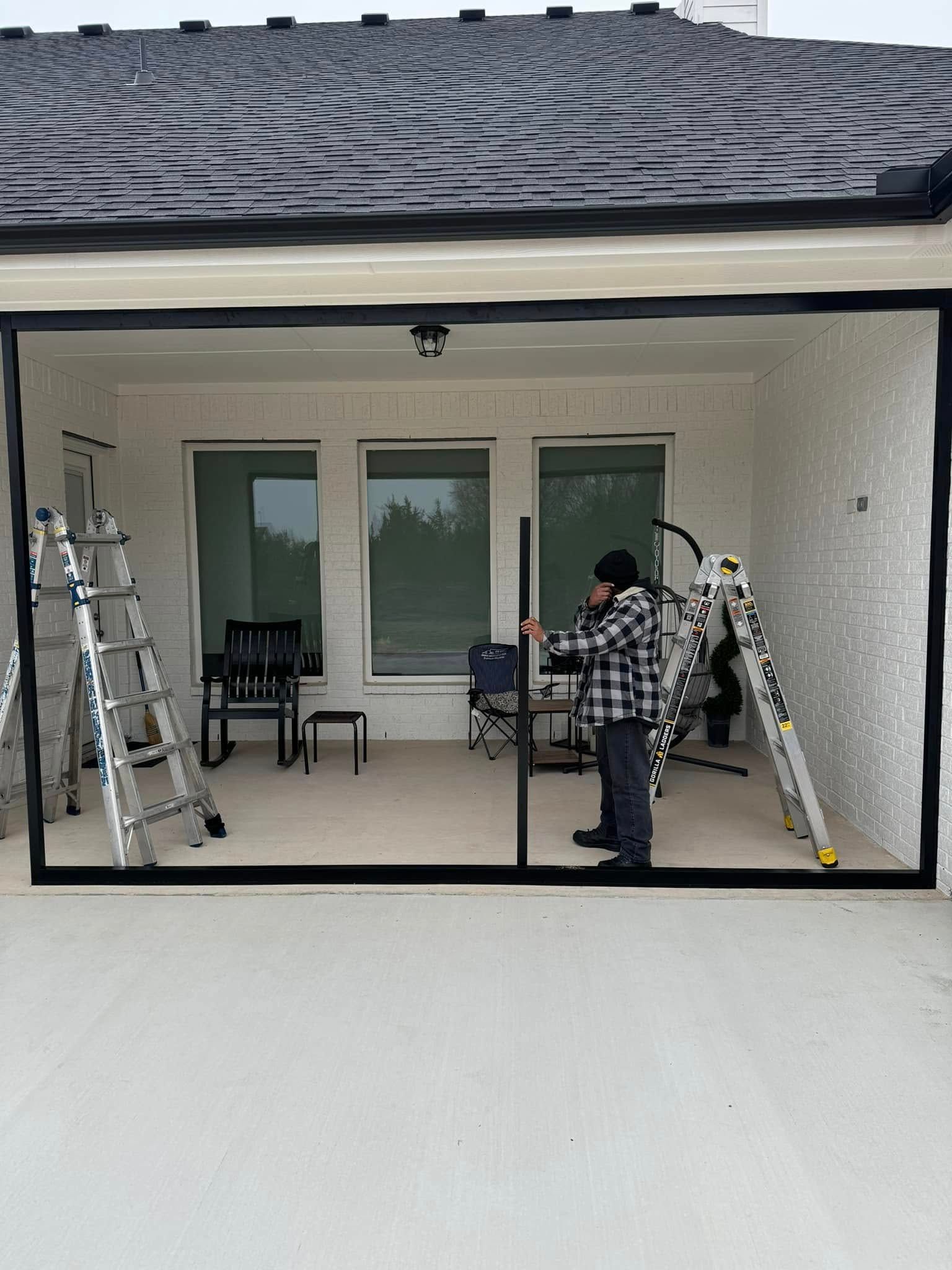 A man is standing in front of a house with a ladder.