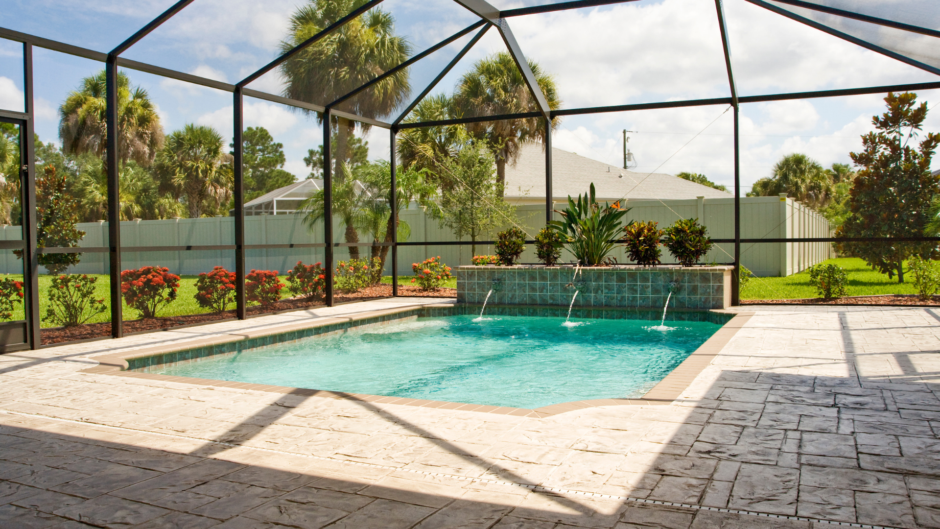 A large swimming pool is surrounded by a screened in area