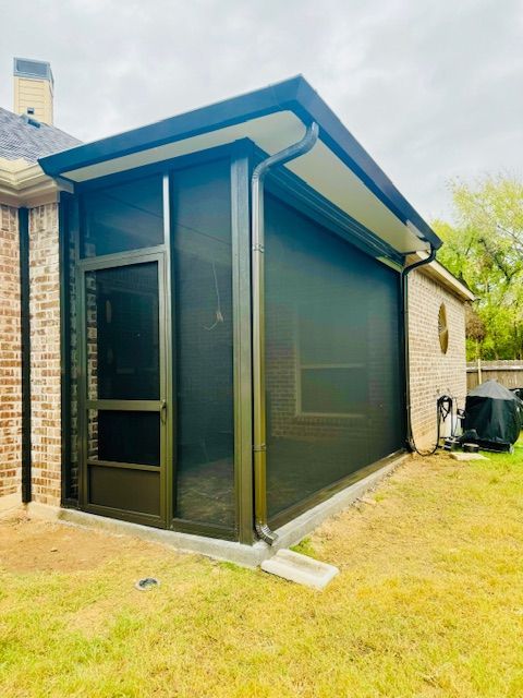A screened in porch on the side of a brick house.