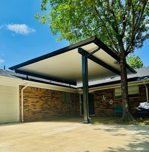 A house with a carport and a tree in front of it.