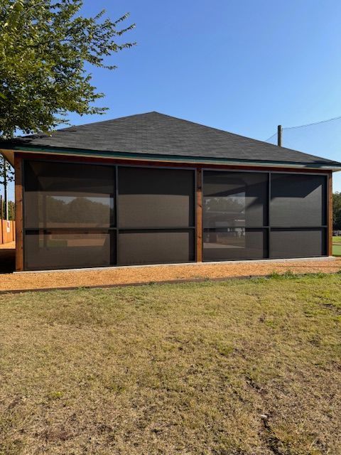 A screened in porch with a roof and a tree in the background
