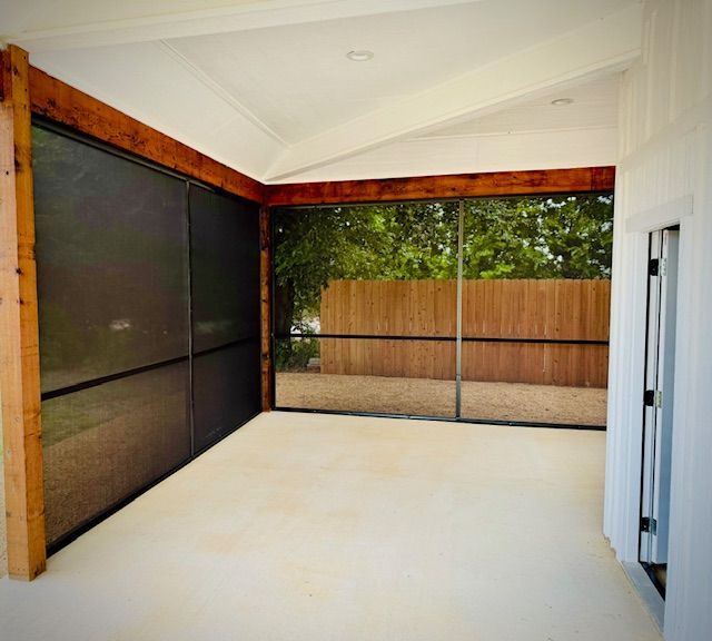 A screened in porch with a wooden fence in the background