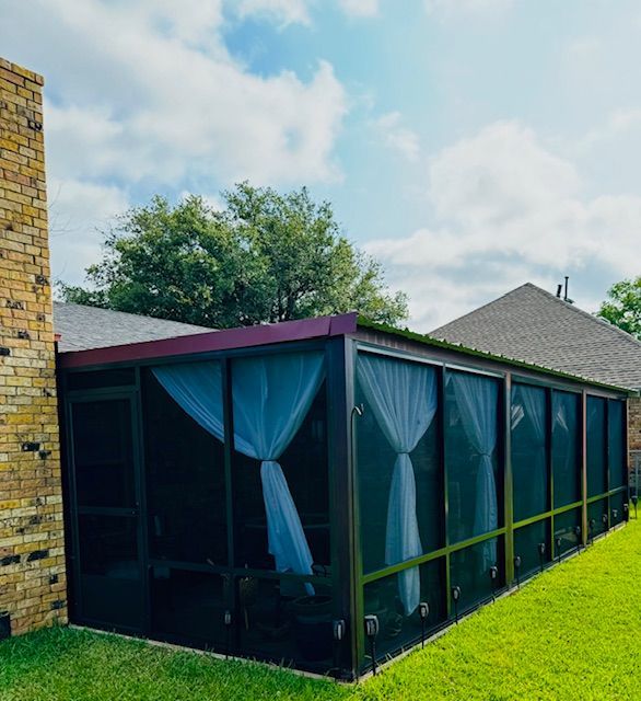 A screened in porch with a brick building in the background