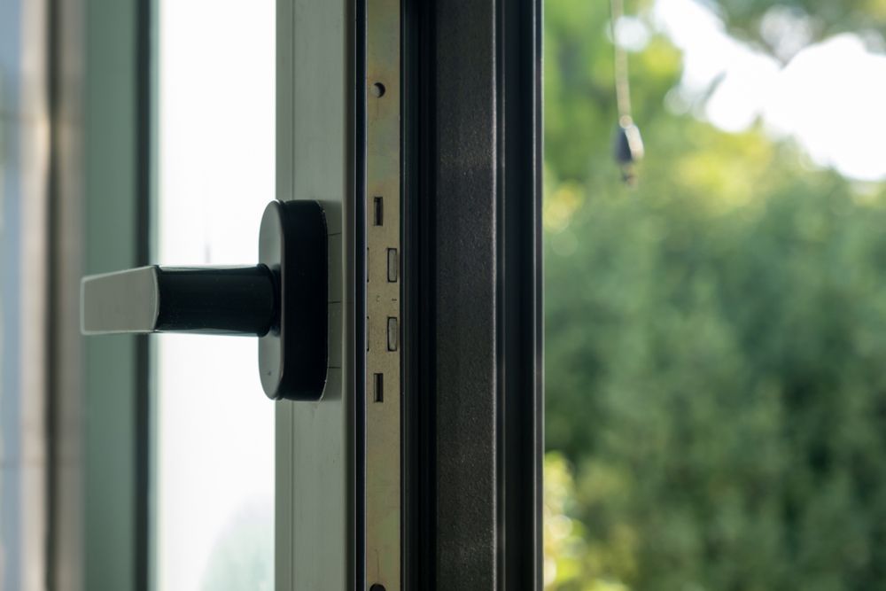A close up of an open window with a black handle.
