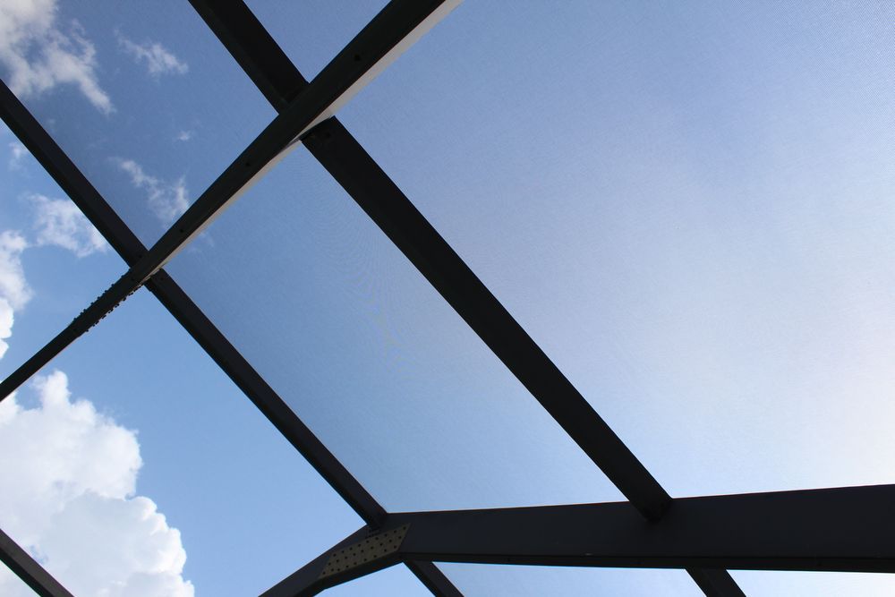 Looking up at a blue sky through a glass roof