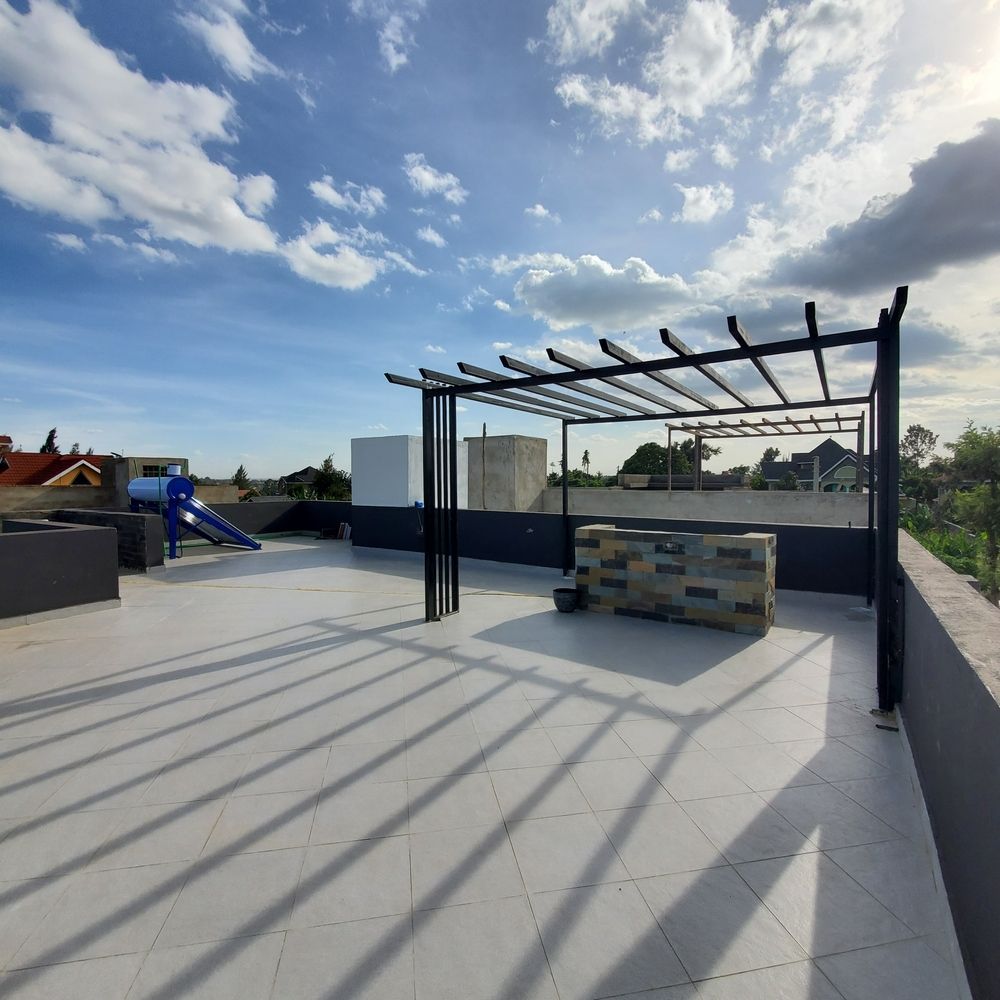 A rooftop with a pergola and a playground in the background