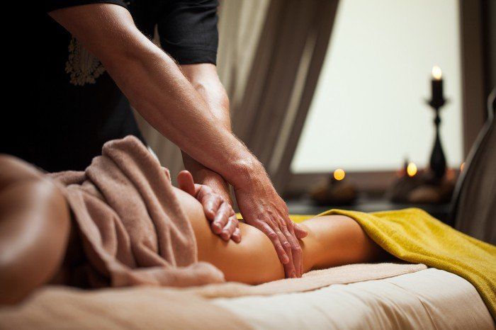 male massage therapist is massaging a female's client's thigh