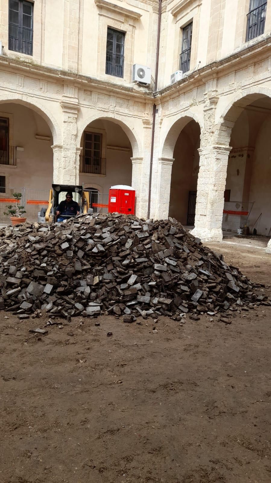 Un bulldozer giallo sta avanzando attraverso un mucchio di terra.