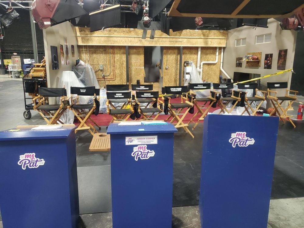 A row of director 's chairs are lined up in front of three blue bins that say my pizza