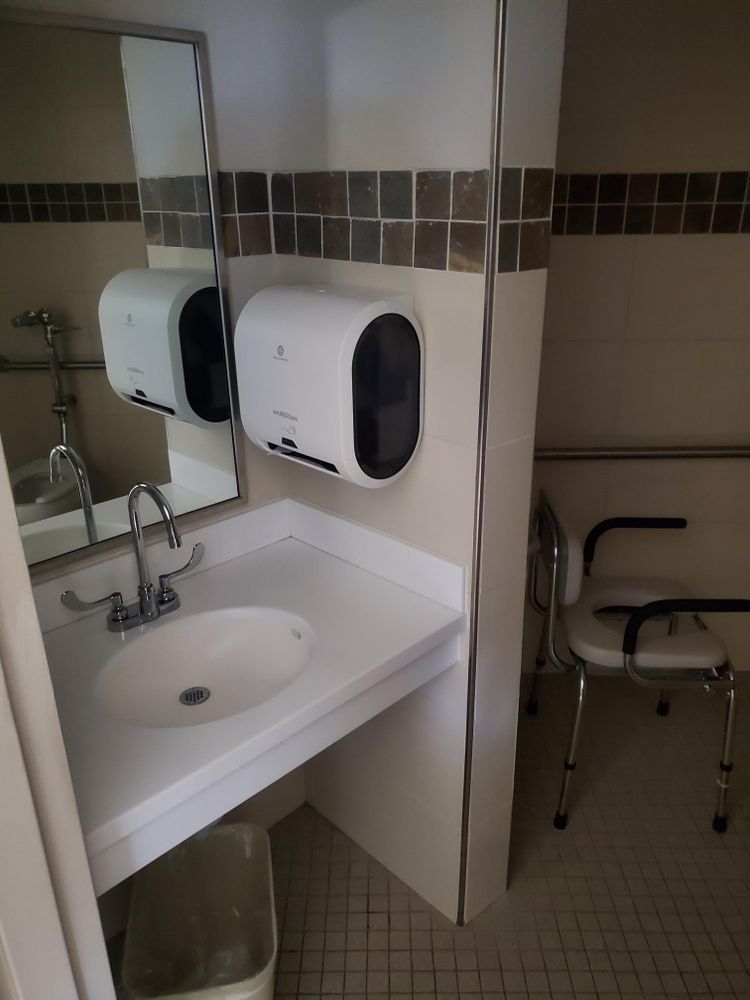 A bathroom with a sink and two paper towels dispensers