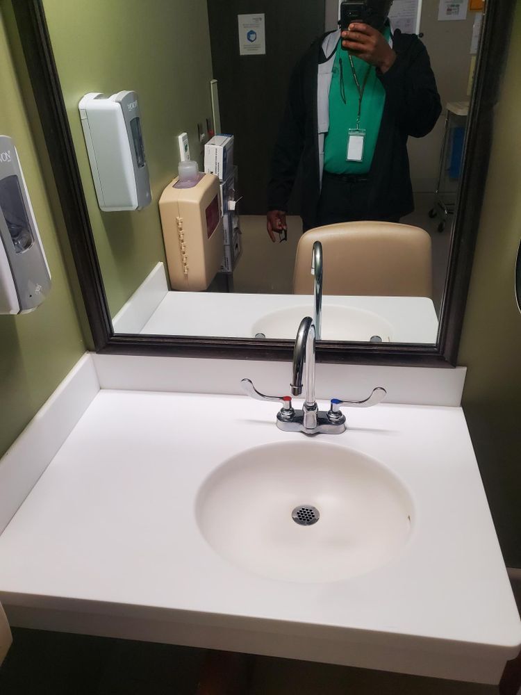 A person is taking a picture of themselves in a bathroom sink