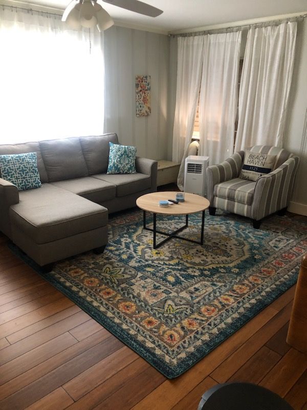 A living room with a couch, chair, coffee table and rug