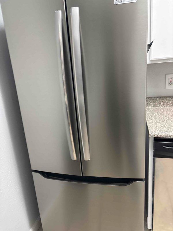 A stainless steel refrigerator is sitting in a kitchen next to a counter