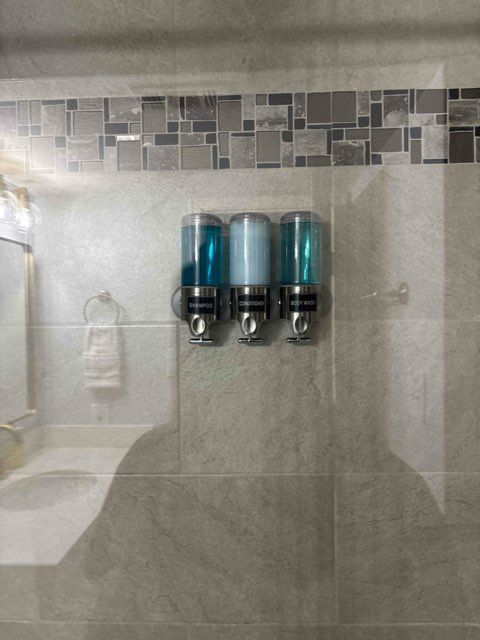 A bathroom with three soap dispensers on the wall