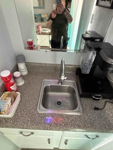 A man is taking a picture of himself in a kitchen sink