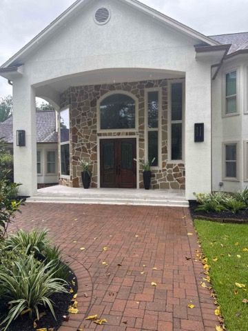 Large home with stone and white facade; red brick walkway.