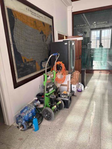 Hallway with equipment: pressure washer, map, boxes, and a closed storefront.