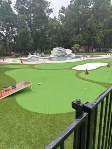 Miniature golf course with green turf, white sand traps, water features, and red flags.
