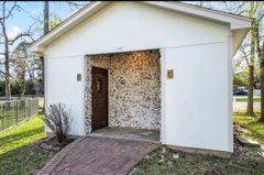 White building with textured stone entry, wooden door, and brick ramp.