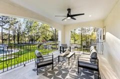 Covered patio with seating, overlooking a landscaped backyard with a pool.