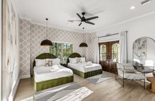 Bedroom with two beds, patterned wallpaper, black pendant lights, and an outdoor view.