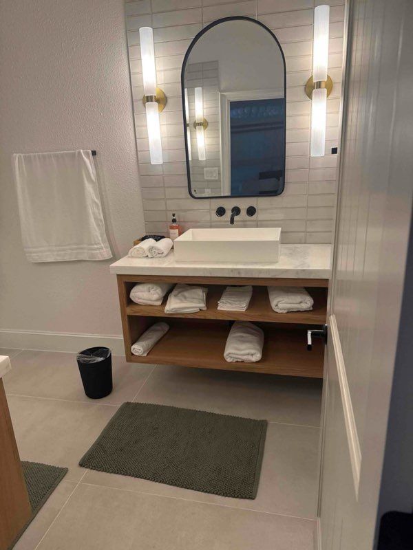 Bathroom with white subway tile, a wooden vanity, and a large mirror.
