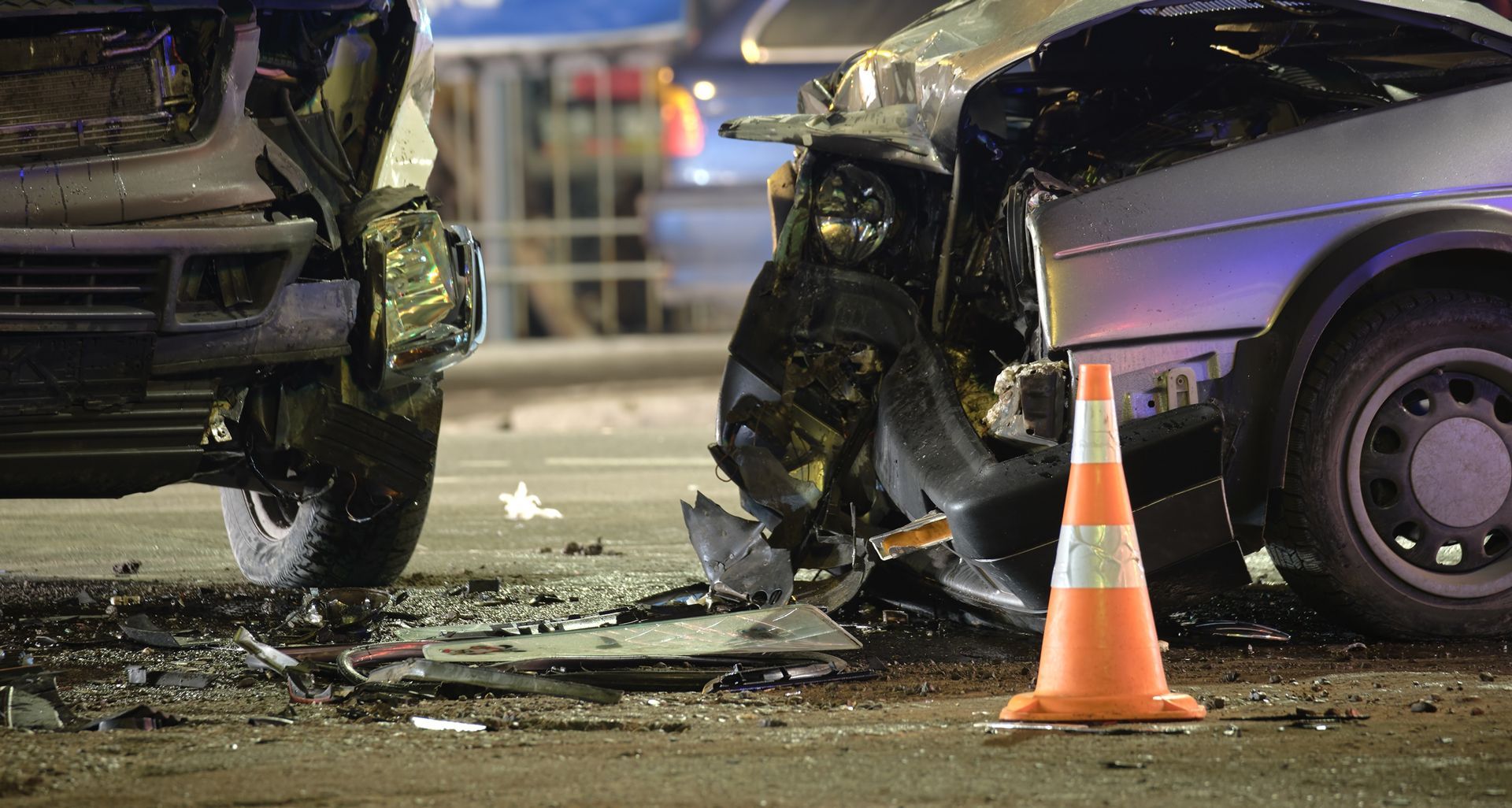 A car accident on a city street with a traffic cone in the foreground