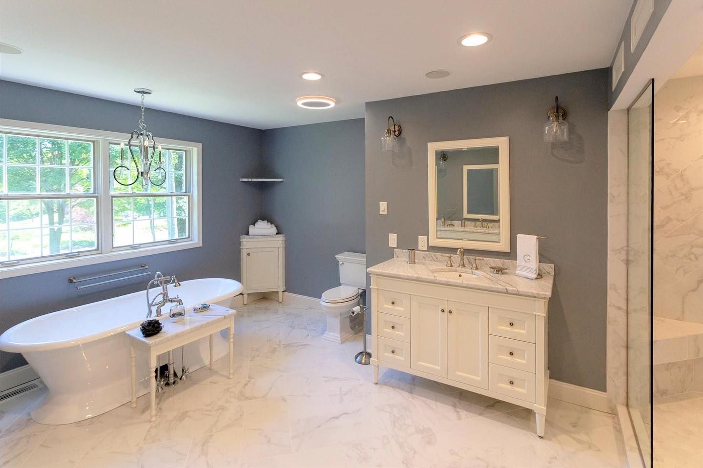 A bathroom with a tub , sink , mirror and window.