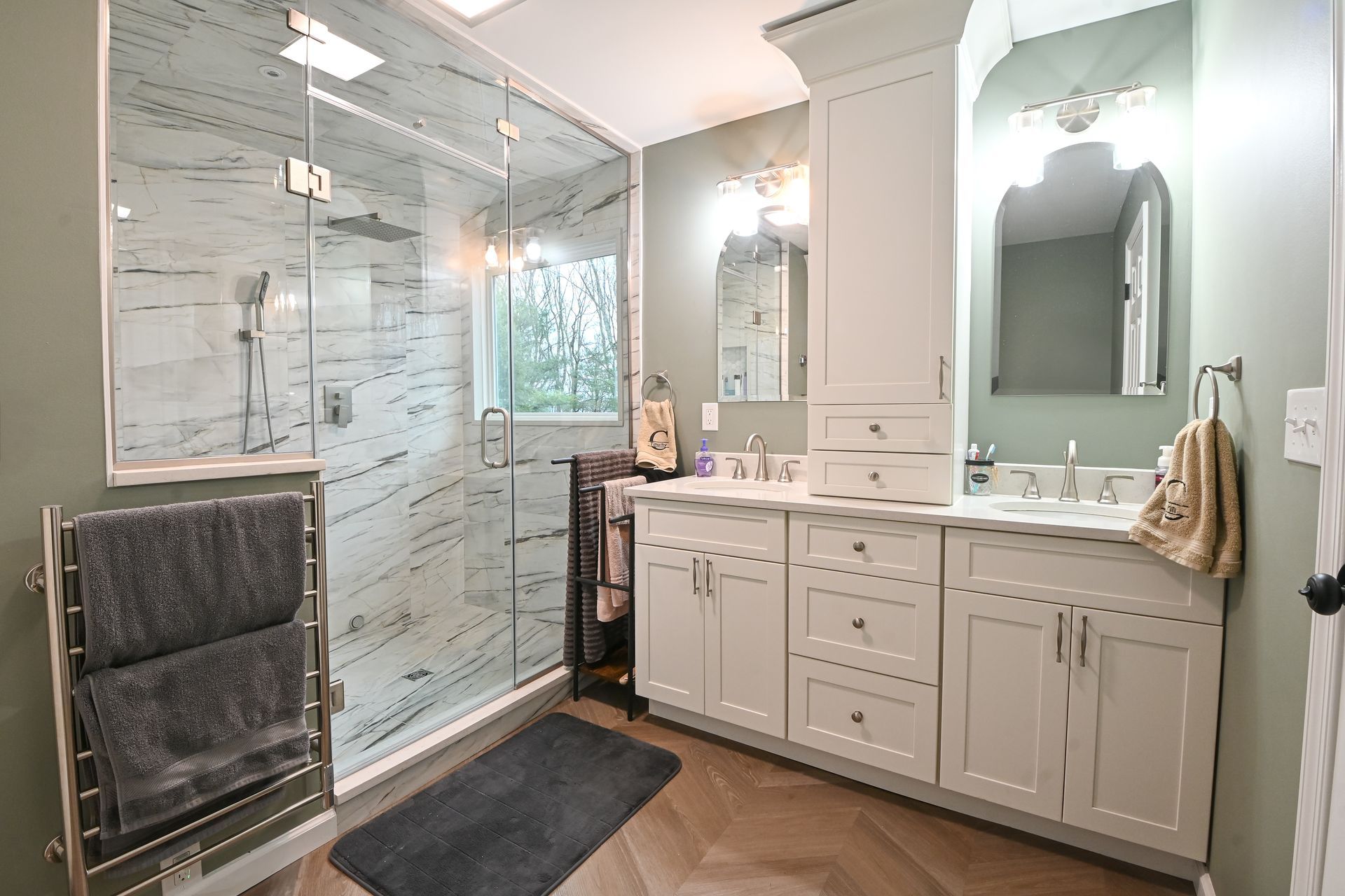 Modern bathroom with a glass shower, double vanity, and heated towel rack.