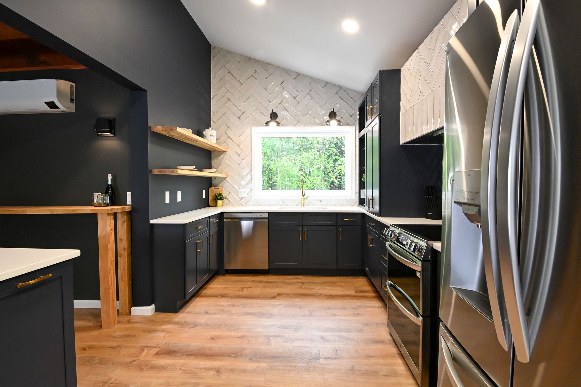 Modern kitchen with dark gray cabinets, stainless steel appliances, and wood flooring.