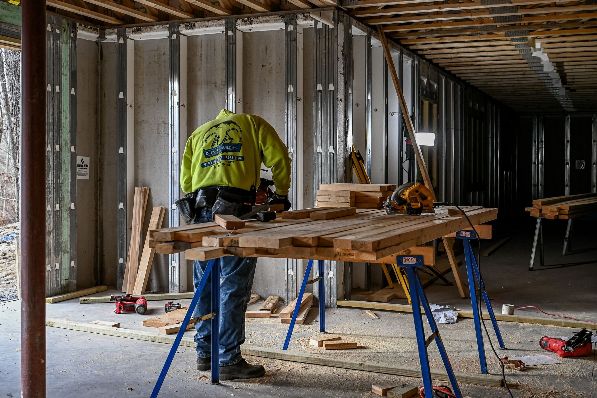 A man is standing next to a wooden table in a room under construction.