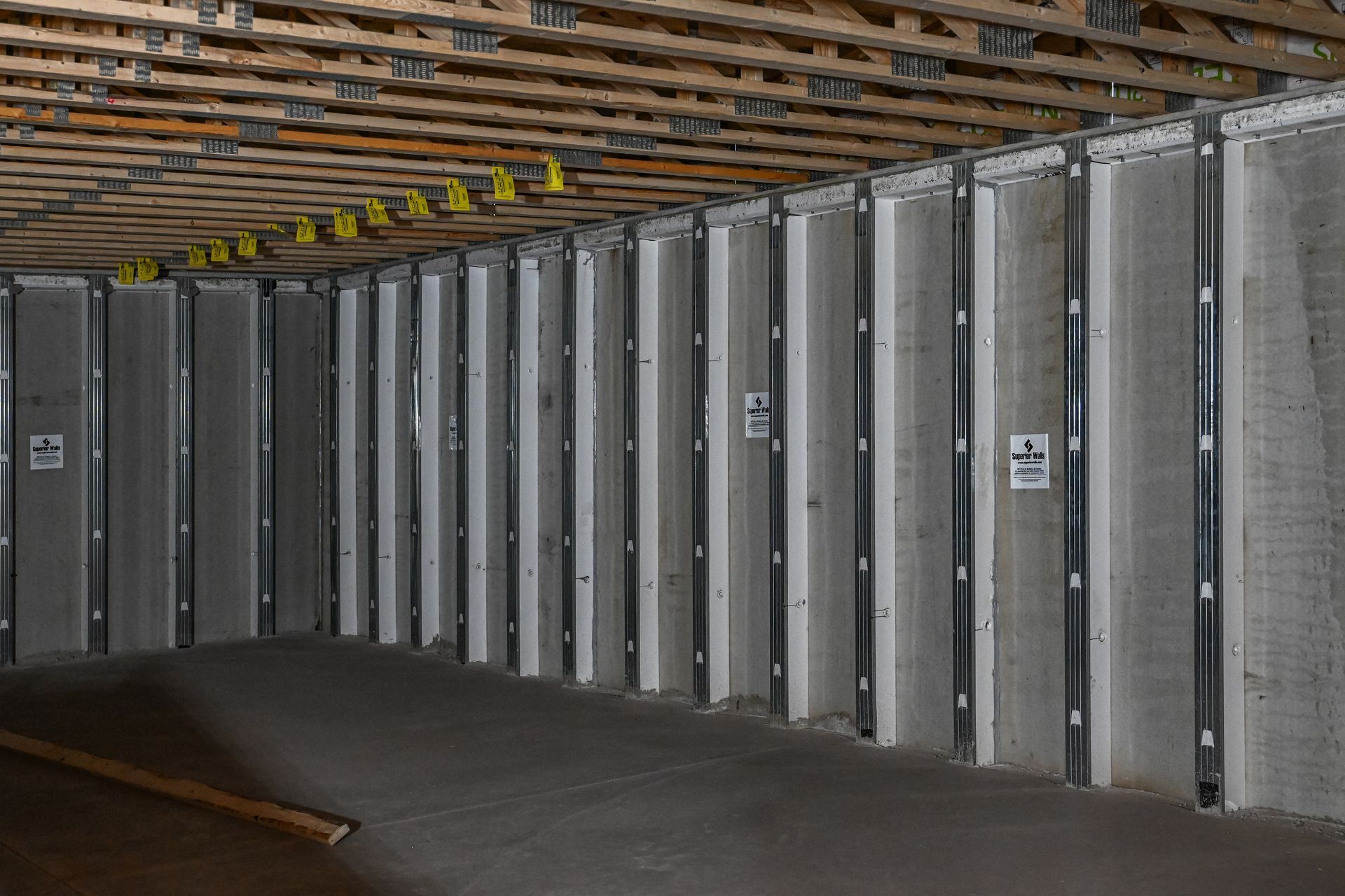 Interior view of a concrete room with vertical gray support beams and wooden supports overhead.