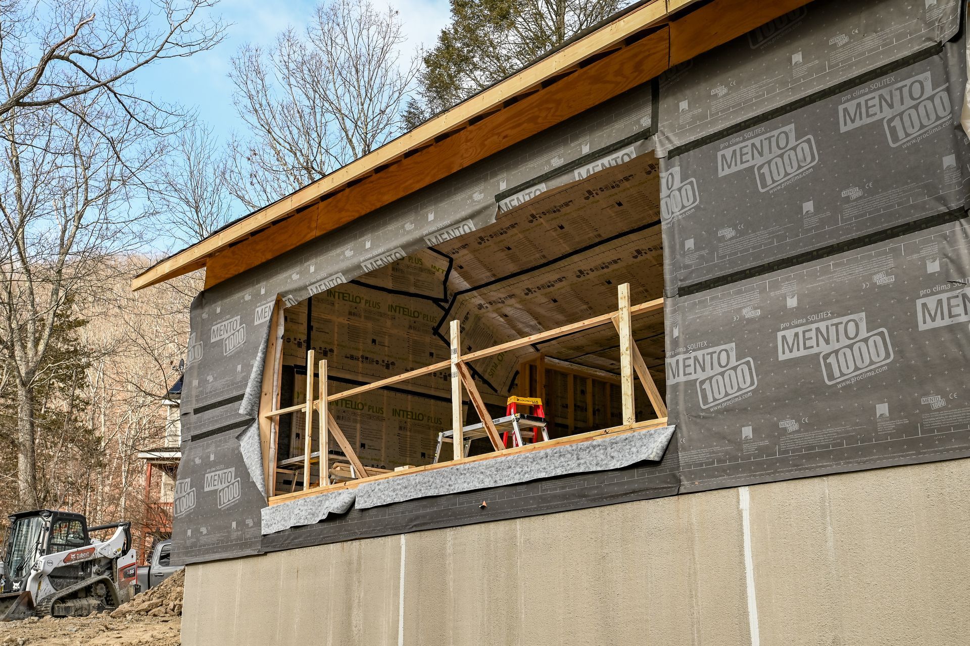Exterior view of a building under construction. Window opening with black weather barrier.