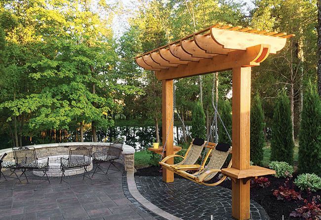 A wooden pergola with a swing underneath it A wooden pergola with a swing underneath it