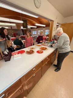 Sue Maxted serving pizza to the kids after they won the food donation for January Mission Moment.