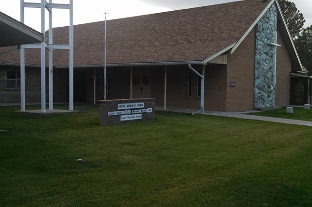 Church building with brown roof, stone accent, sign on lawn, and water tower.
