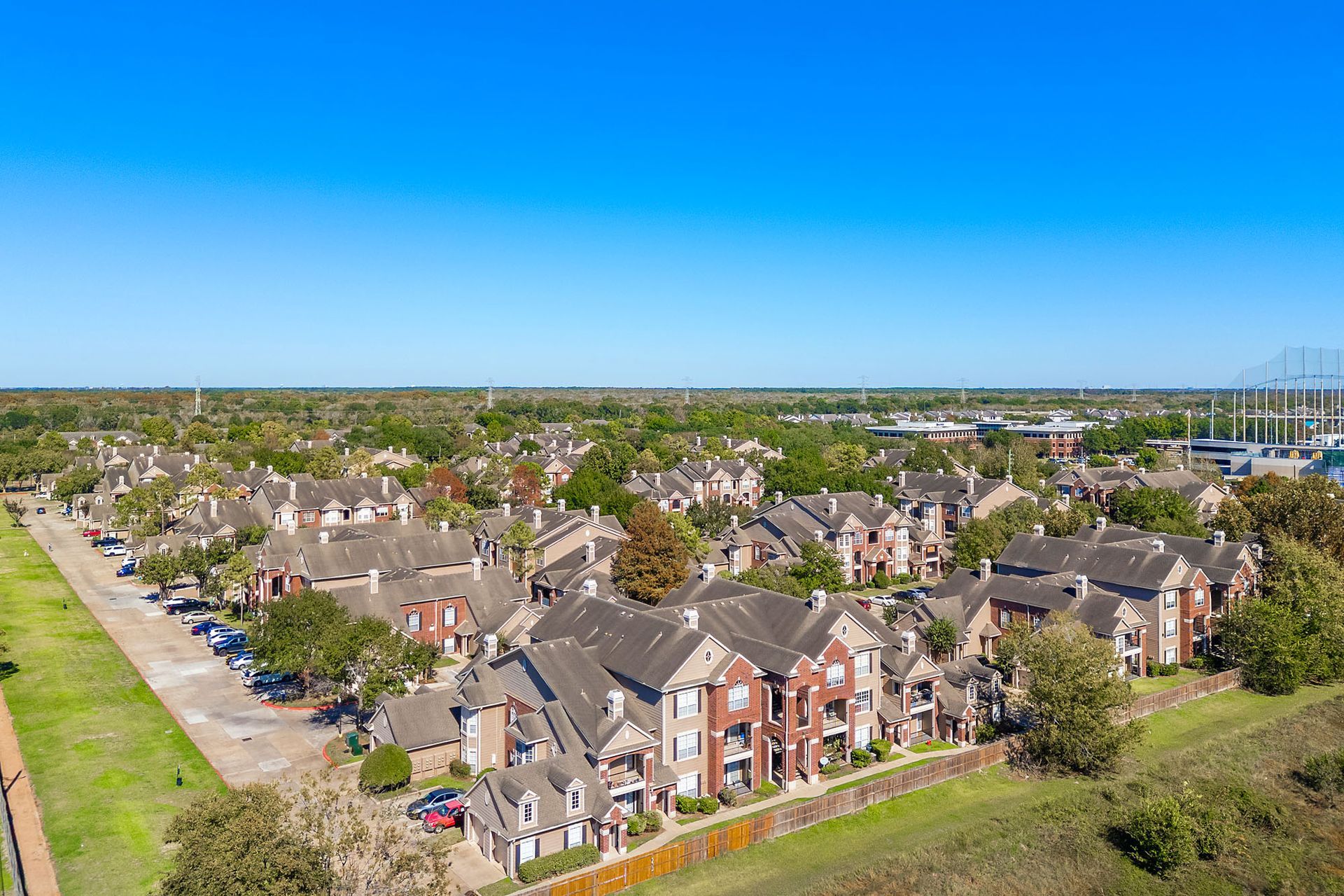 Aerial view of a large apartment community with brick townhomes and green lawns.