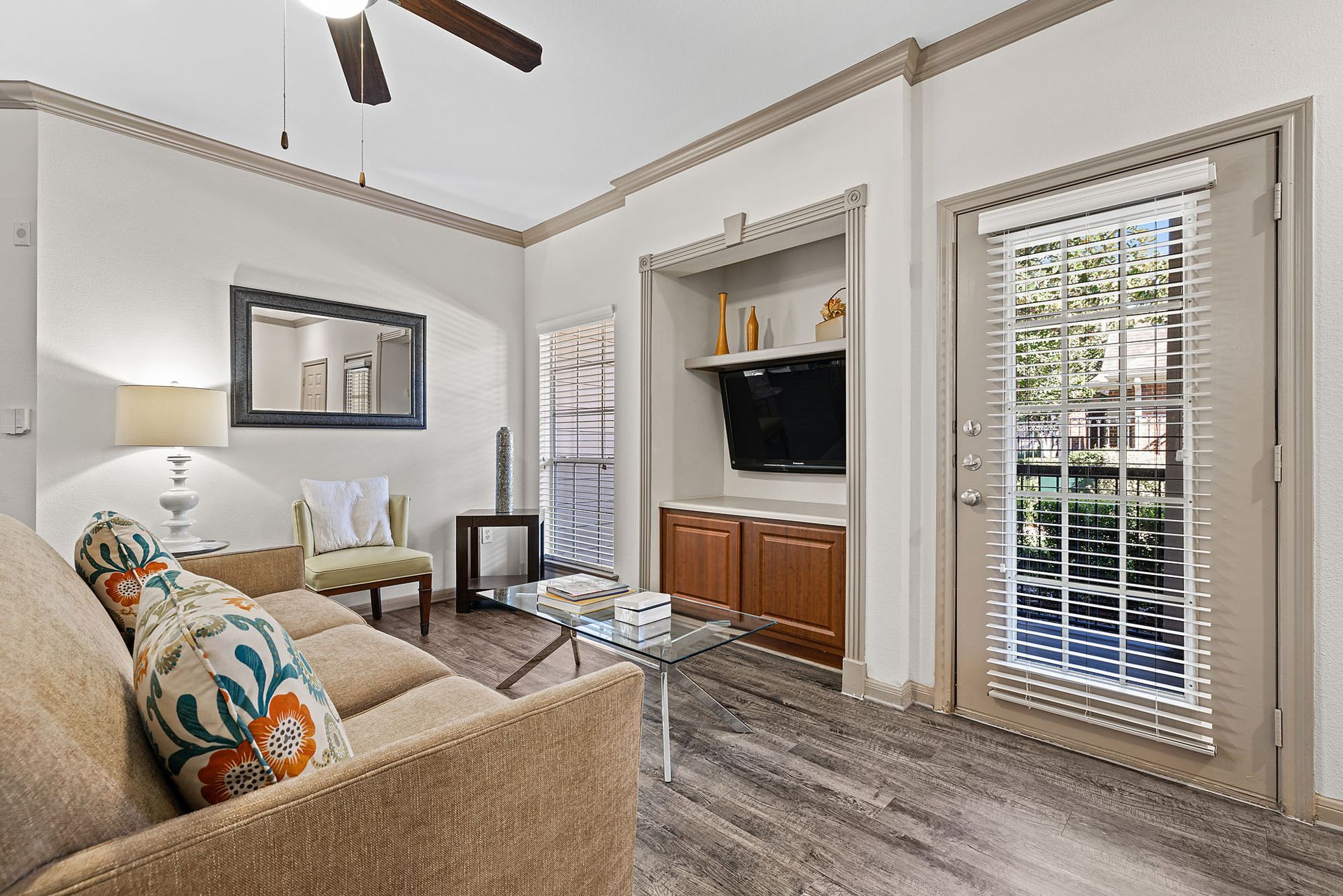 Living room in apartment with beige sofa, glass coffee table, and a built-in TV cabinet.