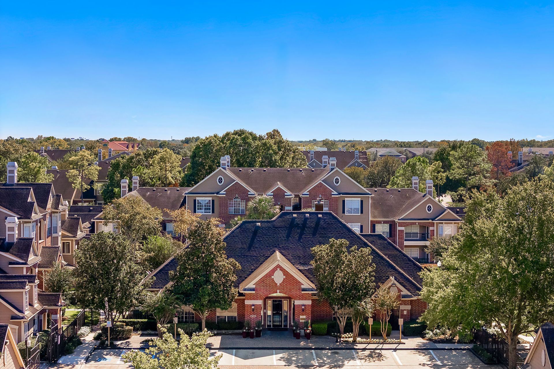 Aerial view of a brick clubhouse and surrounding apartment buildings in a residential community.